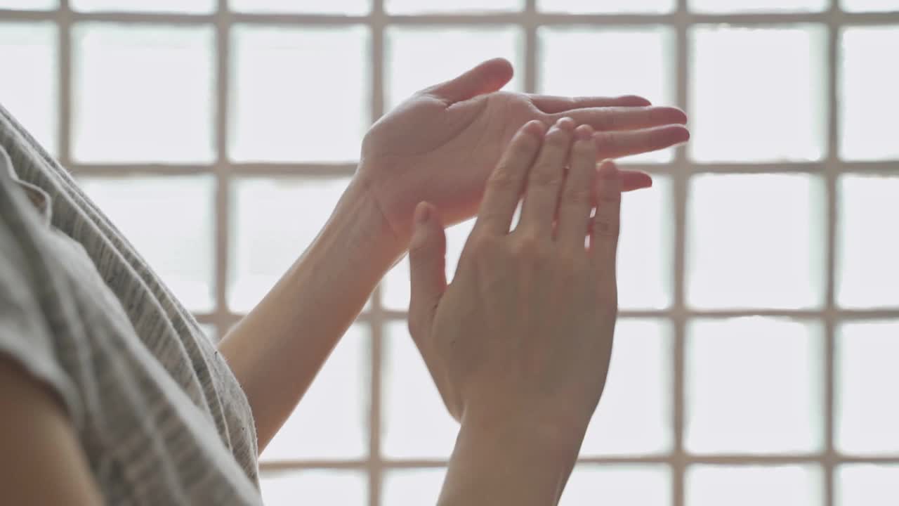 亚洲女性在家庭工作室用乳液在手。白霜擦洗治疗皮肤状况。