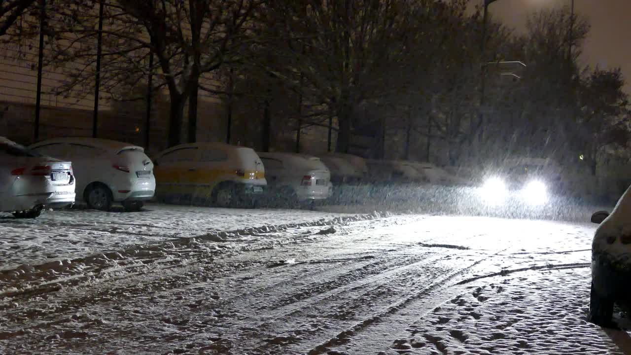 一辆汽车的前灯在夜晚穿过降雪