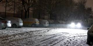一辆汽车的前灯在夜晚穿过降雪