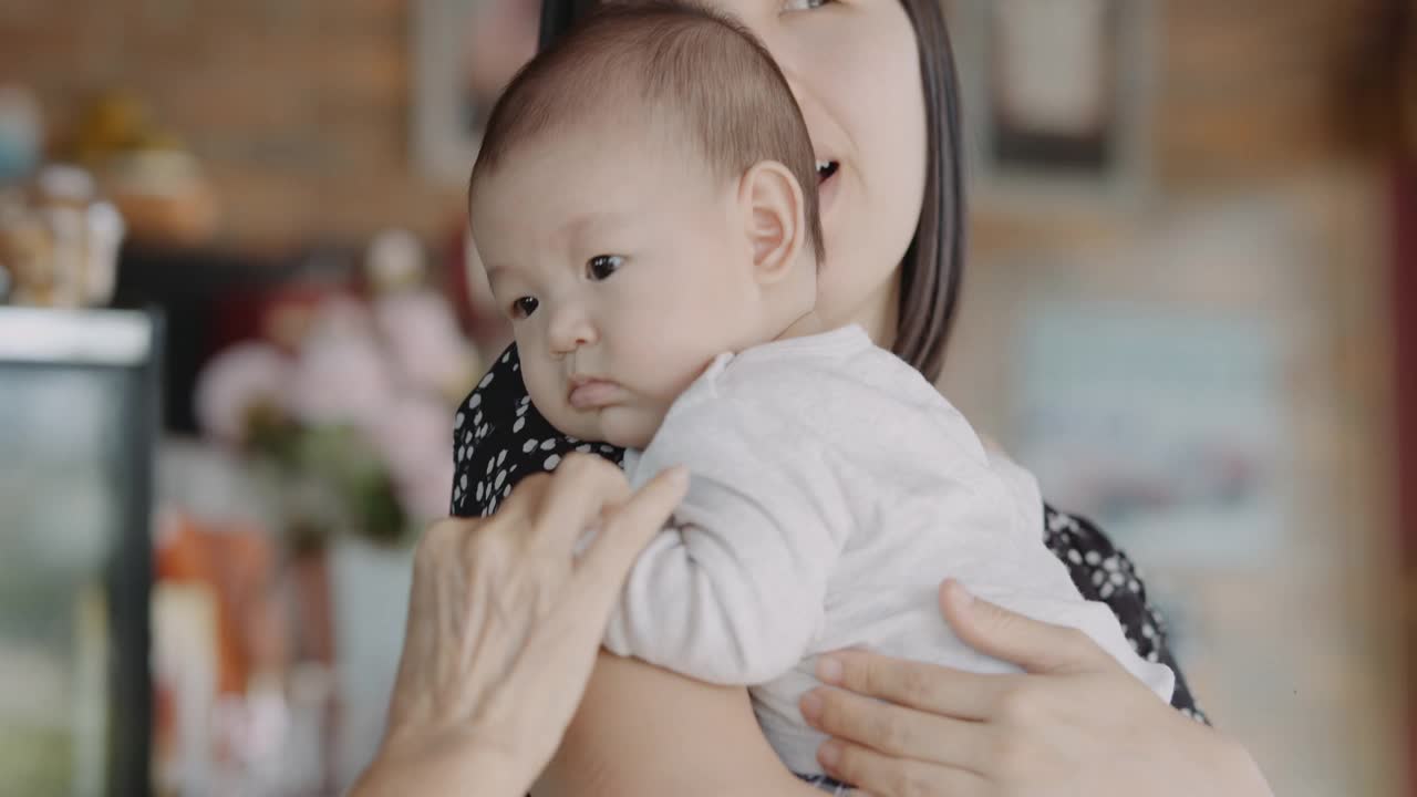 年轻的亚洲妈妈抱着她可爱的儿子