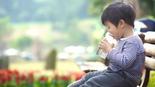 亚洲男婴在公园长凳上喝水视频素材模板下载