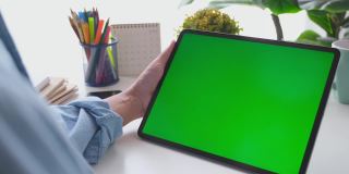 人工手握空白绿屏数码板站在家里的工作台上进行模拟，模板，技术概念