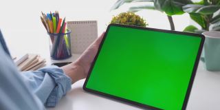 人工手握空白绿屏数码板站在家里的工作台上进行模拟，模板，技术概念