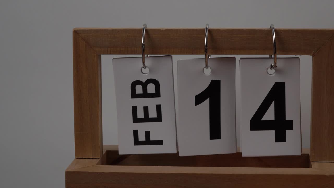 桌面日历与2月14日的日期和一束美丽的鲜花。精致的菊花情人节。手工木历，日期、月份和日期。为一天做计划。