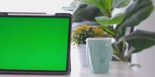 空白绿屏数字平板站在家里的工作台上，模拟，模板，技术概念
