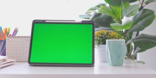 空白绿屏数字平板站在家里的工作台上，模拟，模板，技术概念