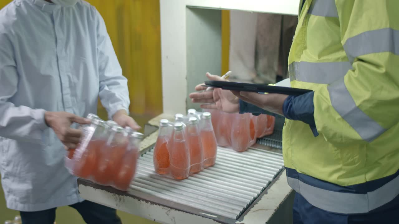 两名工人在传送带上检查排成一排的瓶子