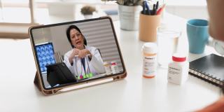 亚洲妇女病人与她的医生视频通话，在家里使用药片要求处方，病人有一个远程顾问关于她的疾病。
