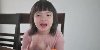 亚洲的中国女孩看着笔记本电脑的摄像头，拿着红包和橘子向她的祖父母祝贺春节