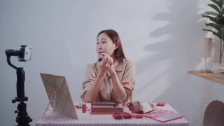 一名亚洲美女博主用智能手机演示如何化妆，并在直播中评论产品视频素材模板下载