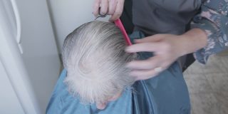 自顶向下拍摄的一个年长的白人妇女在家里理发由专业护理发型师