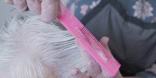 一个年长的白人妇女得到一个专业护理发型师在家里理发的特写镜头