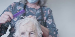一位专业护理发型师在家中理发或洗发时为一位年长的白种妇女梳头