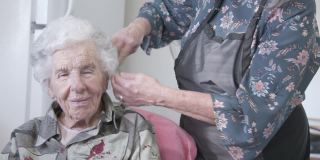 专业护理师在家洗发或烫发后给年长的白人妇女梳头