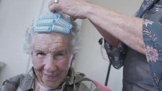 一个专业护理发型师的特写镜头在一个年长的白人妇女的洗发集或在家里烫发视频素材模板下载