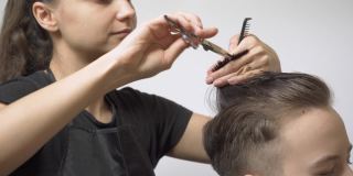 女孩美发师用剪子用尖头技术为客户理发。