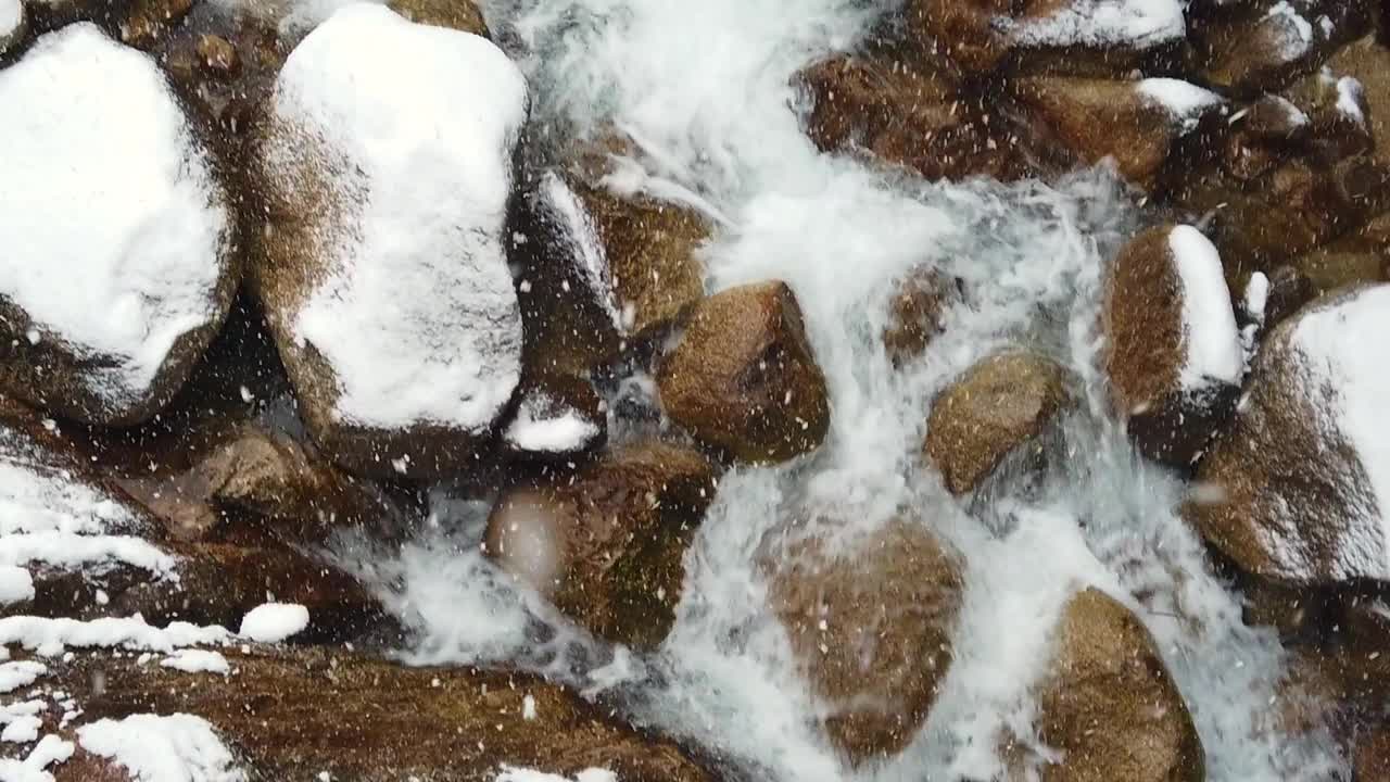 用慢镜头向下看，雪花落在瀑布上，然后向上倾斜