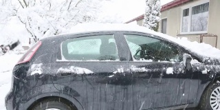 一个成年男子正在清除车上的积雪