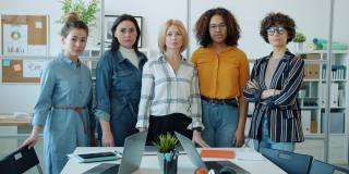 慢动作肖像的不同群体的妇女站在工作场所与严肃的脸