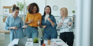 一群年轻和成熟的多种族女性在办公室一起跳舞和大笑