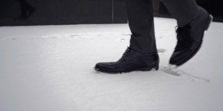 穿着黑鞋的商人。孤独的人走在雪城街道上