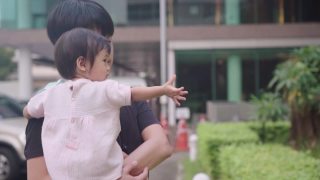 亚洲父亲抱着婴儿环视四周的树木花园公园、停车场，照顾孩子学习和发展，养育亲情，孩子的天真无邪，孩子的好奇心，家庭团聚视频素材模板下载