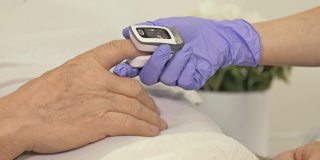 医生戴着乳胶手套测量疑似冠状病毒患者血液中的氧水平。特写镜头
