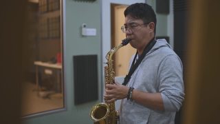 亚洲华人中年男子学习乐器演奏萨克斯在音乐工作室班视频素材模板下载