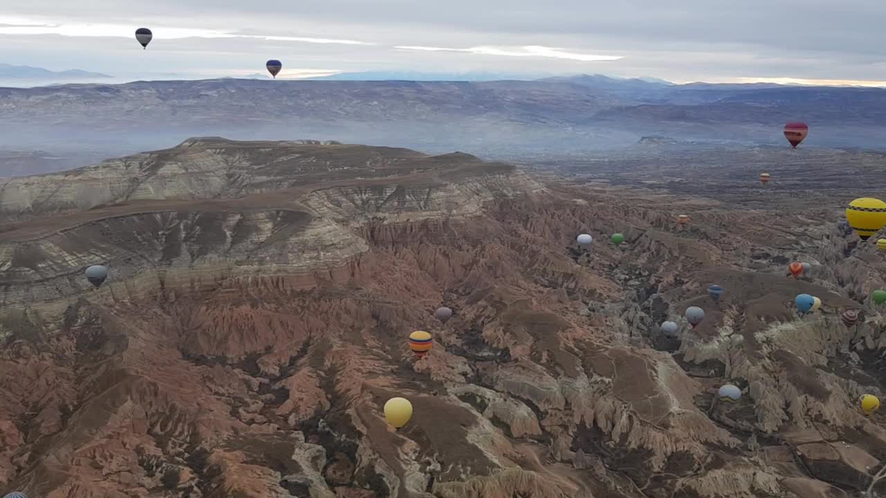 彩色的热气球漂浮在土耳其卡帕多西亚的山景上