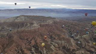 彩色的热气球漂浮在土耳其卡帕多西亚的山景上视频素材模板下载