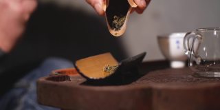 一名男子将茶叶倒进白杨茶托里。木工的艺术手工制作的概念