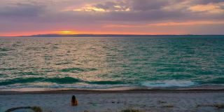 一个女人坐在海边看日落