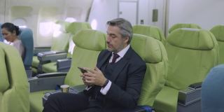 成熟的商人在飞行中使用智能手机