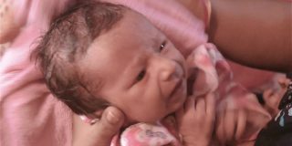 新生婴儿在洗澡。美丽的新生男婴特写(6天大)躺在母亲的膝盖在产前医院。孩子裹着婴儿毯(暖和的衣服)微笑着看。他的母亲安慰和休息她的婴儿。