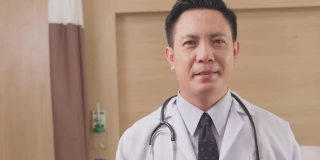 亚洲男医生戴上外科防护口罩，预防冠状病毒大流行。医护人员在医院穿医生袍戴口罩的肖像。健康职业新常态生活方式。