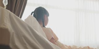 亚洲小女孩戴着口罩躺在康复室的床上，等待家人的探望。父亲微笑着，幸福地拥抱着女儿。