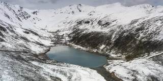 在一个阴天，蓝色的湖躺在雪山的怀抱