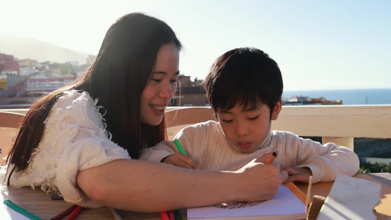 亚洲母亲和儿子一起在户外院子里做作业-学前儿童做绘画活动
