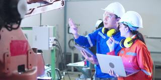 年轻的亚洲工业机器人工程师工作测试和程序机器人手臂在一个研究实验室与现代设备一起。人与科技或创新的观念。