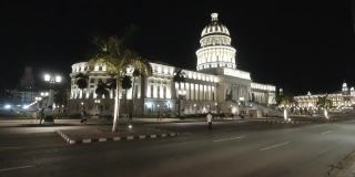 高清拍摄的老爷车通过城市街道的老哈瓦那与首都大厦的背景在哈瓦那，古巴晚上