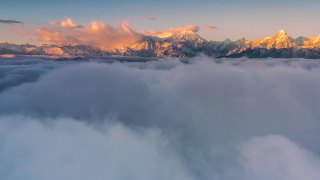 日出时，云海在雪山前翻滚，显得格外壮观视频素材模板下载