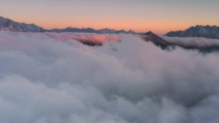 日出时，云海在雪山前翻滚，显得格外壮观视频素材模板下载