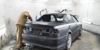 汽车行业的专业修理工，在车身喷漆前对金属车身进行砂光处理