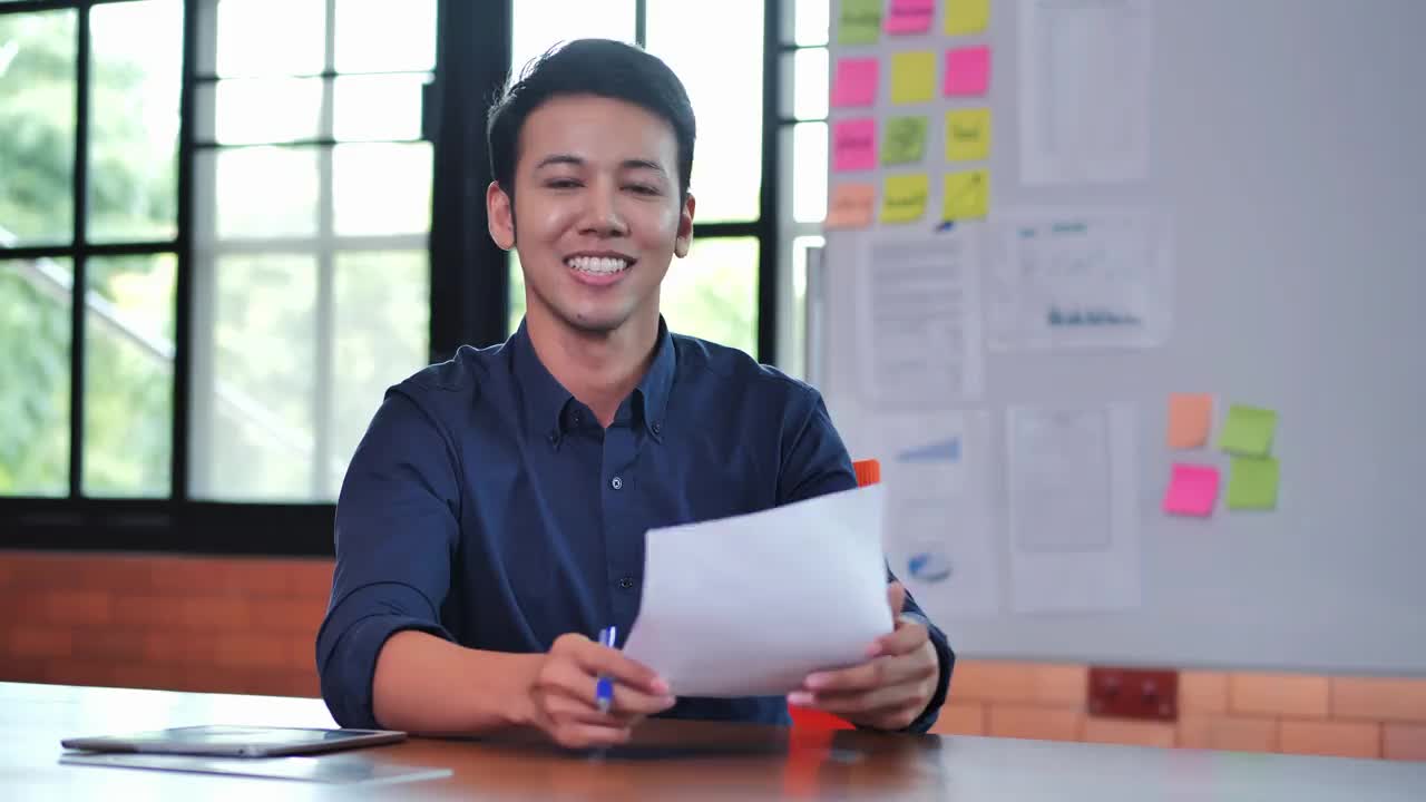 32岁的亚洲商人微笑着看着现代办公室里充满自信的镜头。工作的骄傲概念。