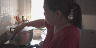 年长的亚洲妇女在家做饭。
