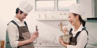 两个亚洲人在家里一起做饭时拍照