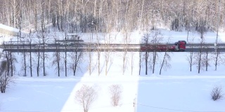 汽车、卡车、救护车在冬季的公路、高速公路上行驶，以积雪和森林为背景，从上面射出阳光