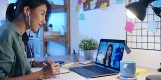 亚洲女商人在起居室用笔记本电脑和同事讨论视频会议的计划。