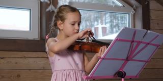 小女孩在家里拉小提琴和锻炼身体