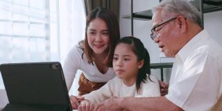 爷爷和妈妈一边教女儿做作业，一边在家上网学习。